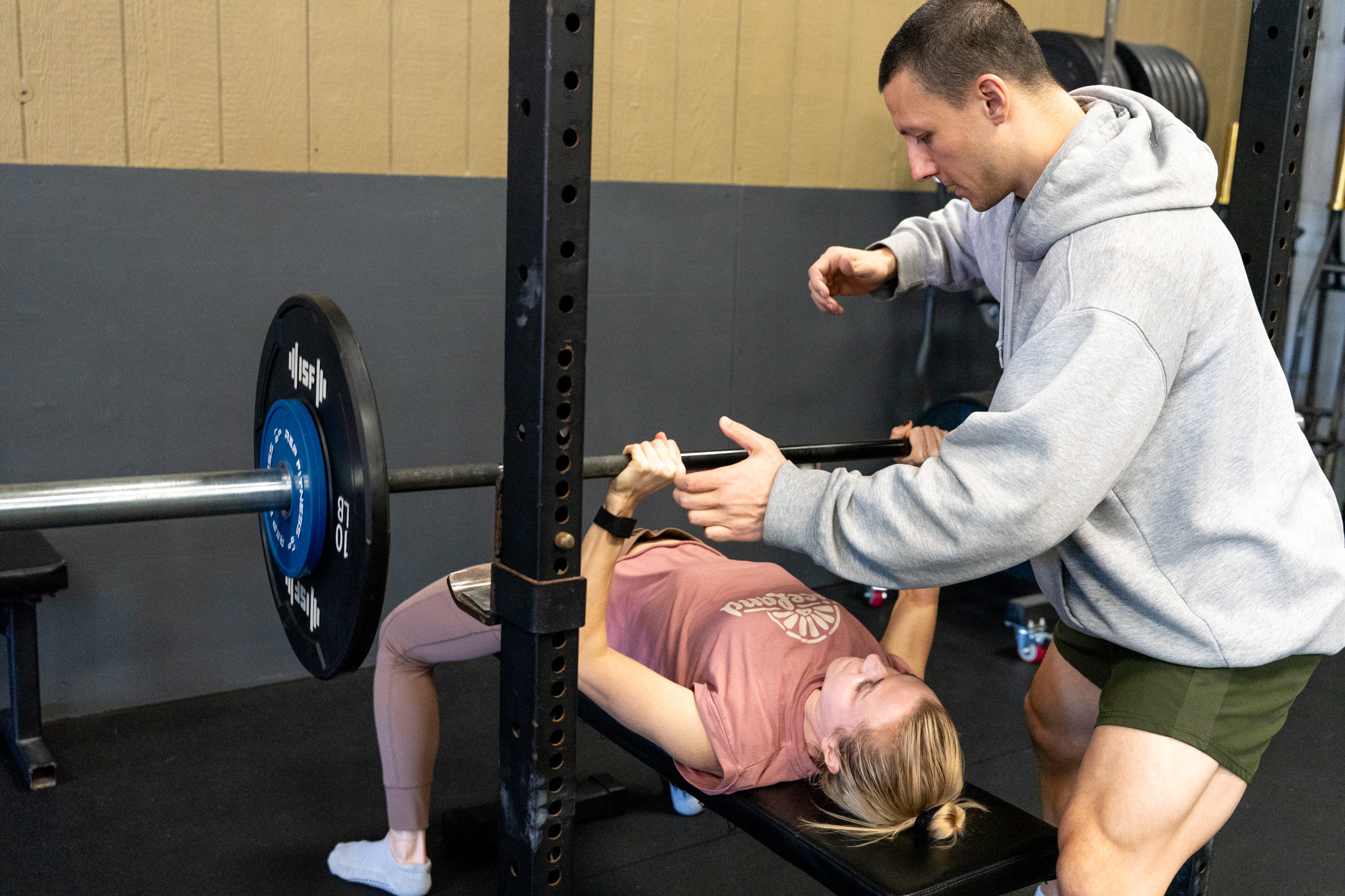 Coach spotting a member during a bench press in small group training at Grounded Performance ATX in North Austin